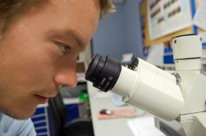 מדען מסתכל במיקרוסקופ - ביטוח אחריות מקצועית